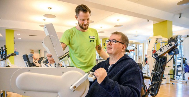 Tomas Gerlach mit seinem Physiotherapeuten im Fitnesstudio am Armtrainer